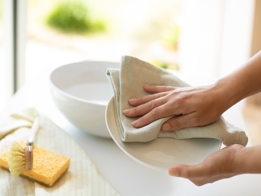 Ein Teller wird in der Küche mit einem Tuch abgetrocknet