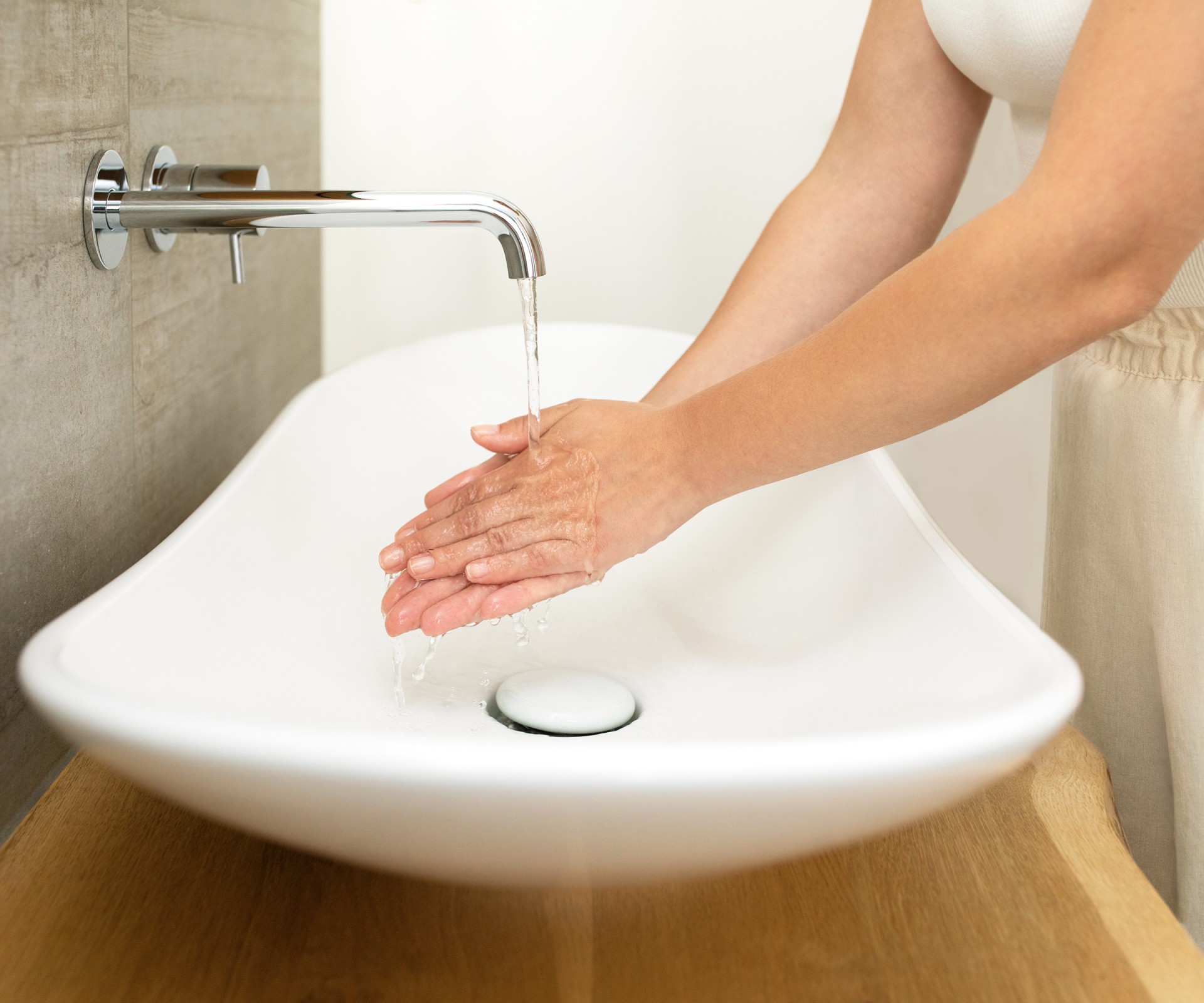 Eine Person wäscht sich an einem Waschbecken im Bad die Hände