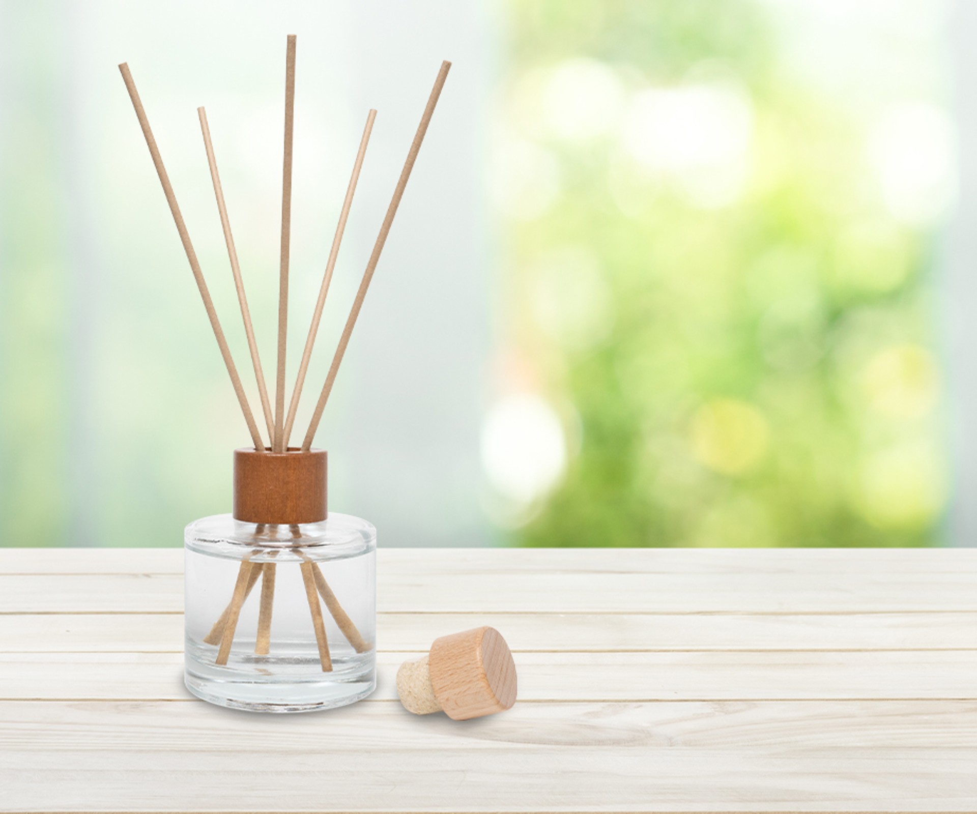 A Frosch Oase room freshener glass bottle with reed diffusers stands on a wooden table