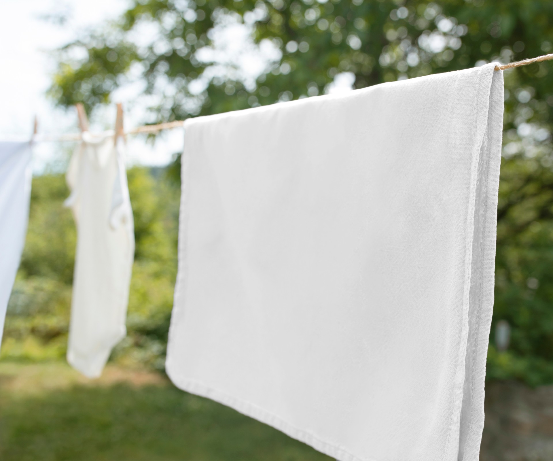 An einer Wäscheleine im Freien hängen Tücher und Kleidung